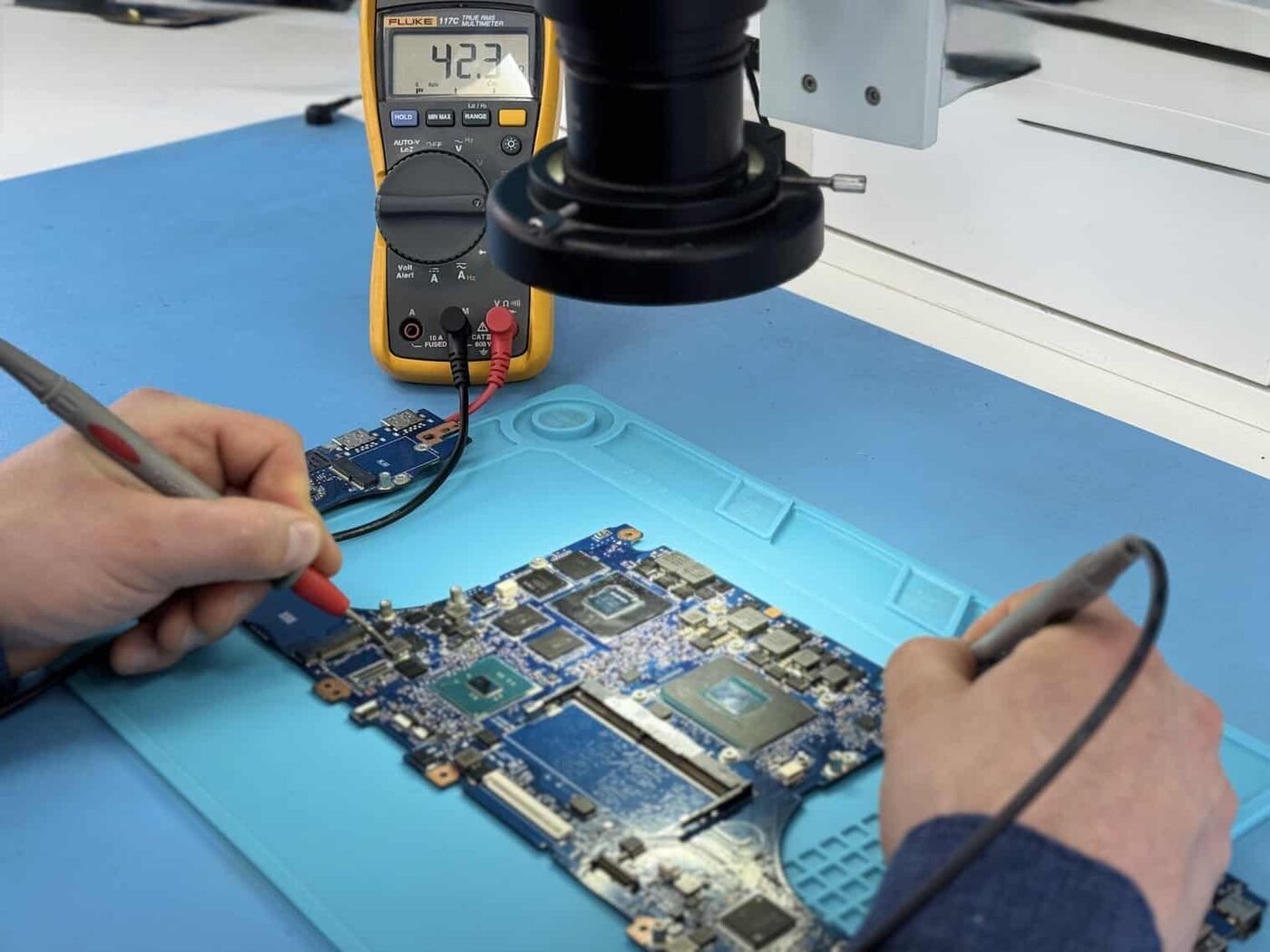 Circuit board being probed with a multimeter during component-level diagnosis
